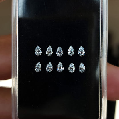 Representative pear diamond stock arranged crown-up in two rows inside a black display case.