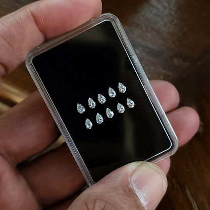 Angled hand-held display case showing representative pear brilliant diamonds arranged crown-up.