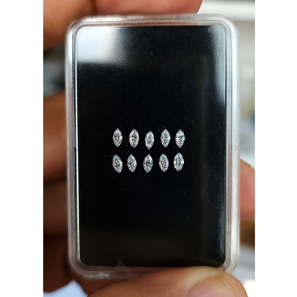 ダークな生地の上に置かれた代表的な3x1.5mm天然マーキースダイヤモンドのグループ。