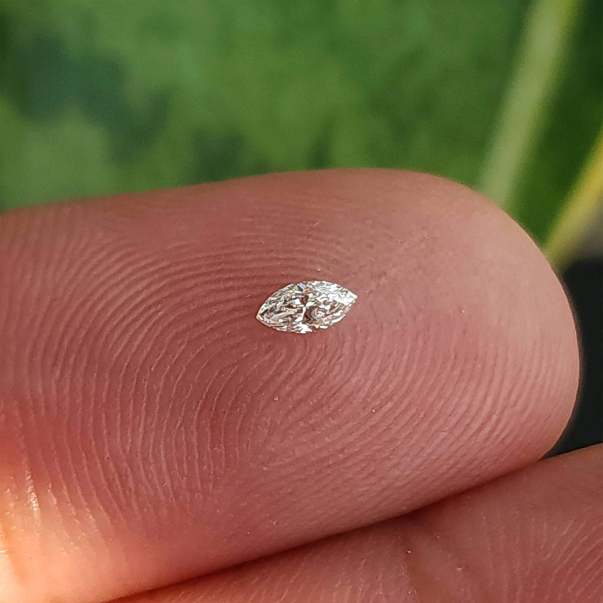 指先に置いた代表的な小さなマーキースダイヤモンド1石。規格サイズ3x1.5mmの目安を示しています。