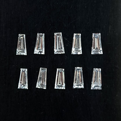 Diamantes naturales baguette trapezoidales dispuestos en dos filas sobre un cojín negro, mostrando tablas planas transparentes y facetas escalonadas.