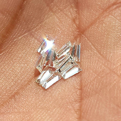 Diamantes baguette trapezoidales agrupados sobre la piel, con reflejos fuertes y brillantes a través de varias piedras.