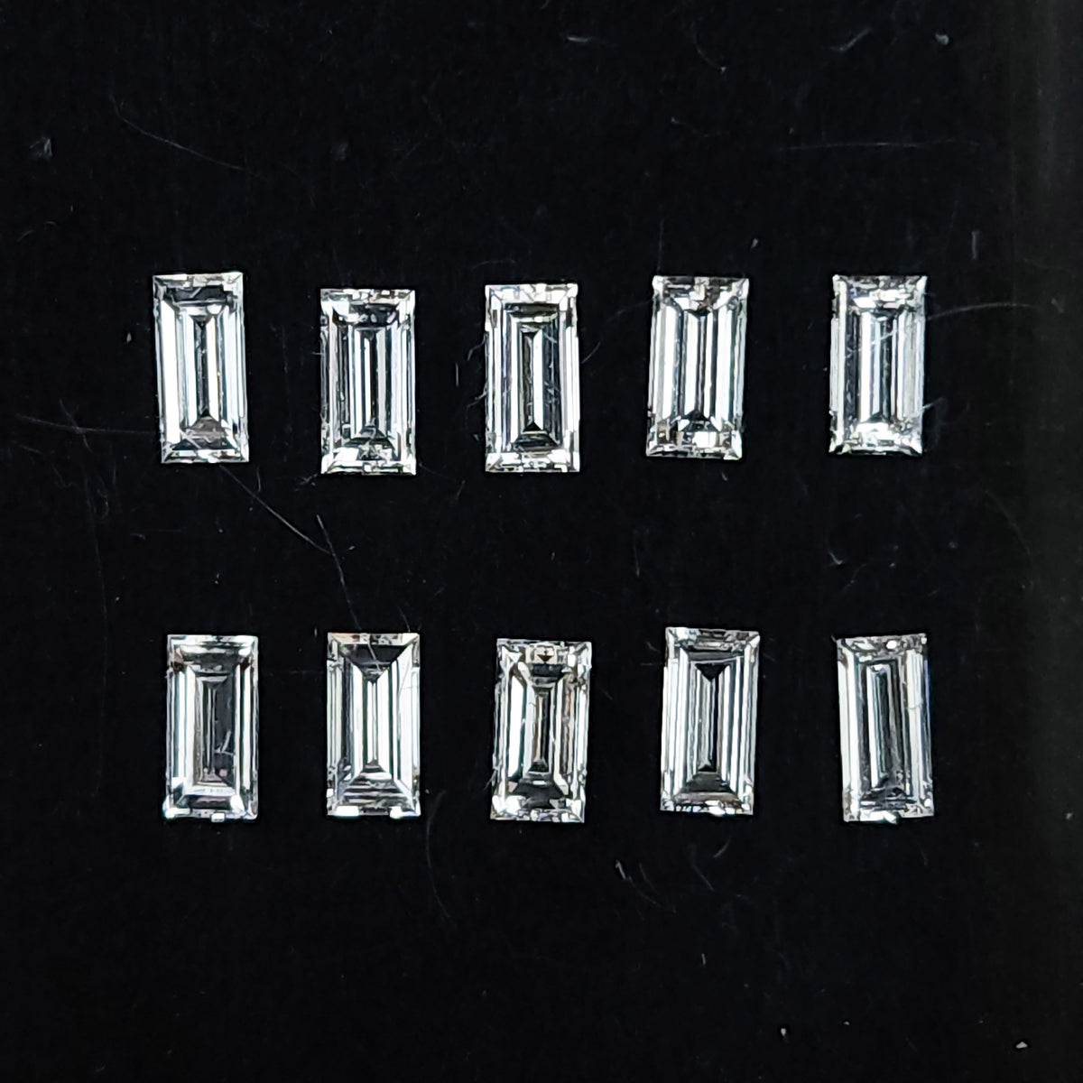 Representative natural baguette step-cut diamonds arranged face up on a dark background; sold per piece.