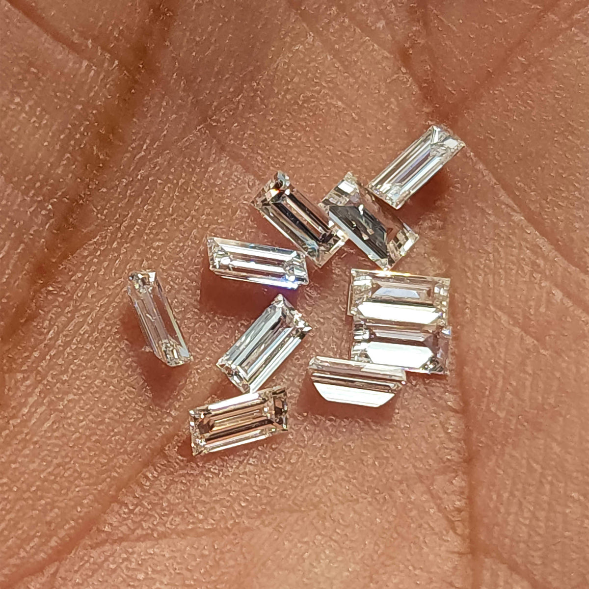 Representative baguette diamonds in mixed orientations on an open palm for scale.