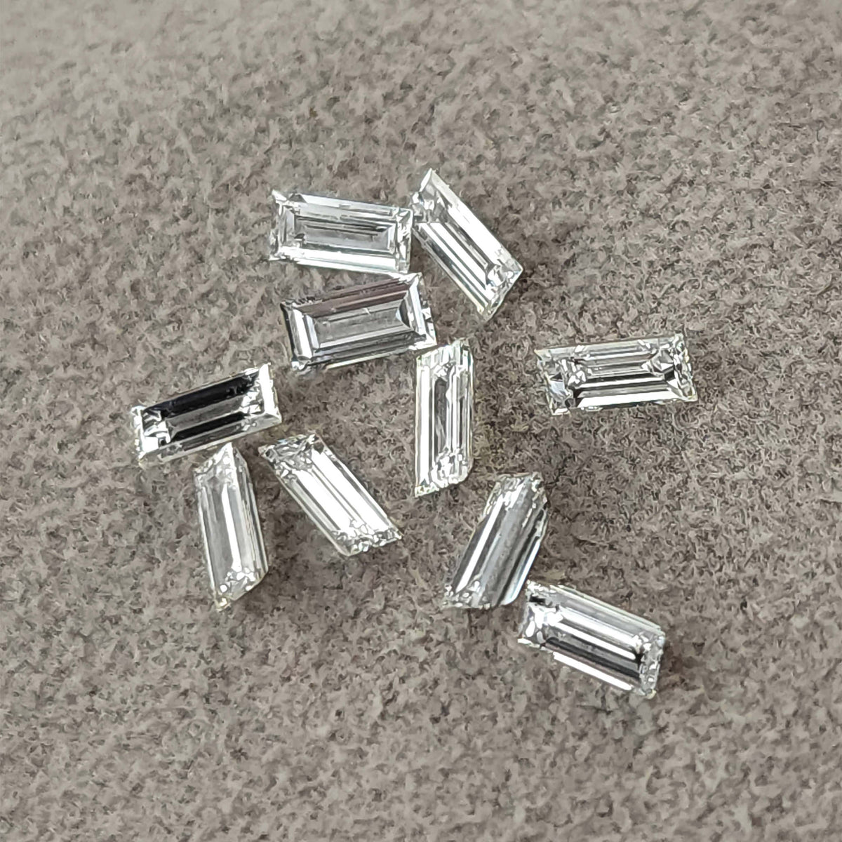 Representative natural baguette step-cut diamonds arranged on gray fabric.