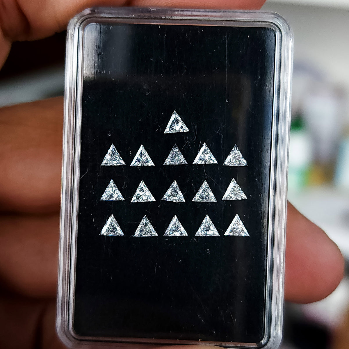 Black display box of triangle diamonds held between fingers, showing a representative supply parcel rather than a one-purchase quantity.