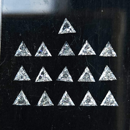 Close face-up group of triangle diamonds in a black display box, with pointed outlines and brilliant facets visible across the parcel.