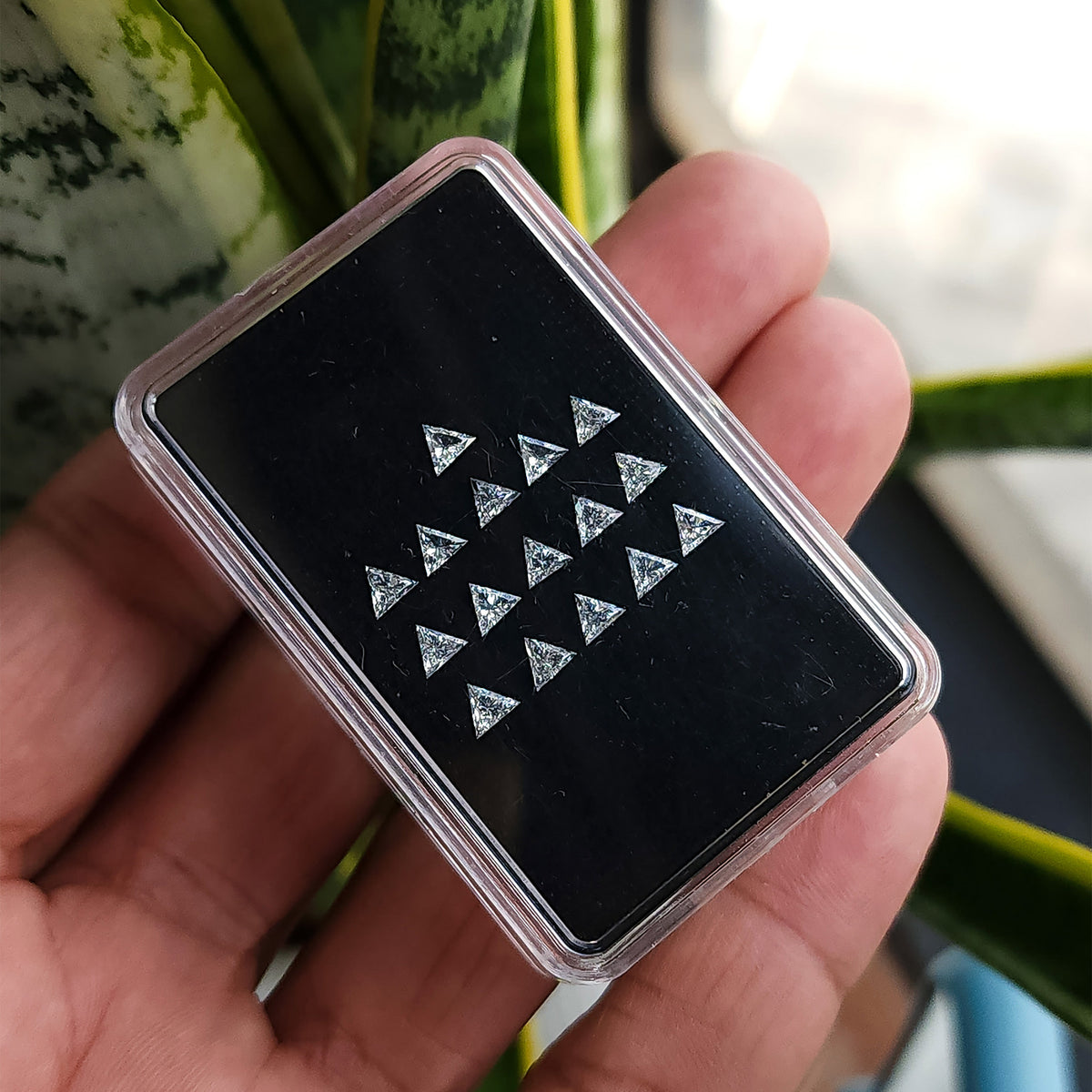 Triangle-diamond display box tilted across a palm, illustrating representative stock and changing facet reflections.