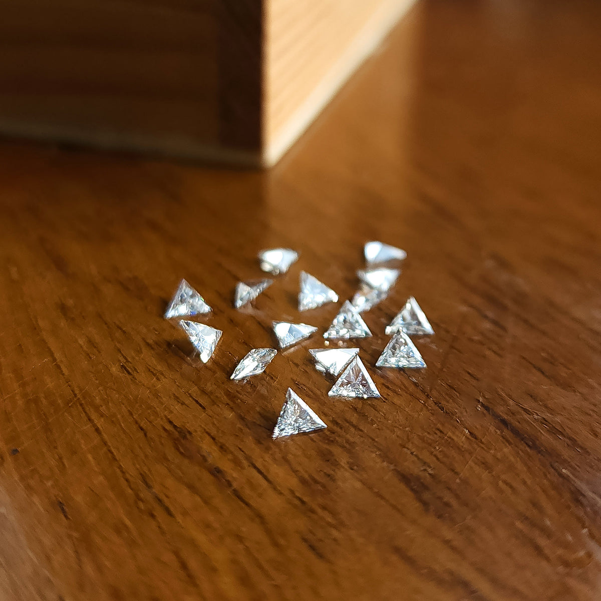 Loose triangle-diamond group on wood, with individual stones at different tilts; representative parcel rather than the purchase unit.