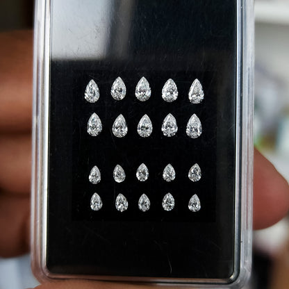 Representative pear diamond stock arranged crown-up in upper and lower size groups inside a black case.