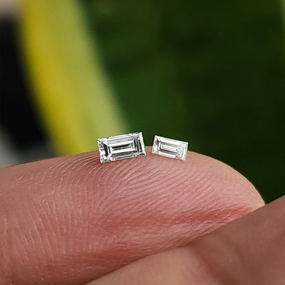 Two representative natural baguette diamonds on a fingertip showing the two offered sizes.