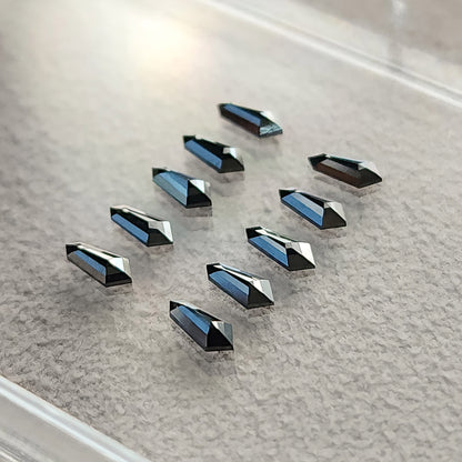 Angled black shield-diamond group on gray paper, showing depth and blue-gray highlights on reflective facets.