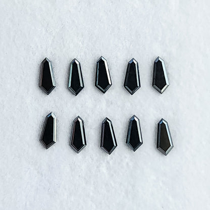 Ten face-up black shield diamonds in two rows on a white surface, showing dark centers and pale edge reflections.