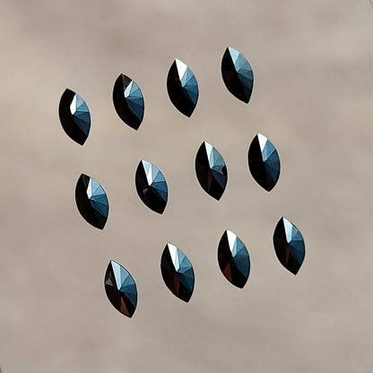 Twelve black marquise diamonds in rows with their centrally converging opposite-side facets facing the camera.