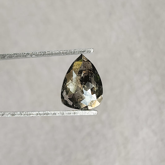 Pear-shaped salt-and-pepper diamond held face-up in tweezers on a light gray background, showing mixed dark inclusions and bright facet reflections.