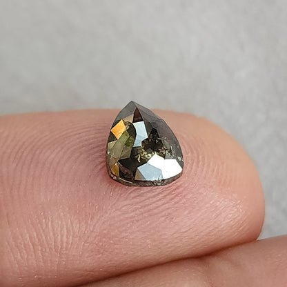 指先に載せたペアシェイプの石を斜めから見た画像。上部のファセット全体に、鏡のような広い反射が見える。