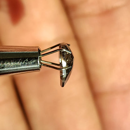 プロングツールで持ったペアシェイプの石の側面。平らなベースからわずかに盛り上がっている様子が見える。