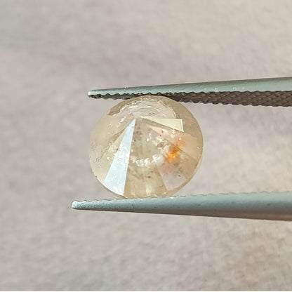 Pavilion side of the round diamond held in tweezers, showing converging underside facets and a warm inclusion near the center.
