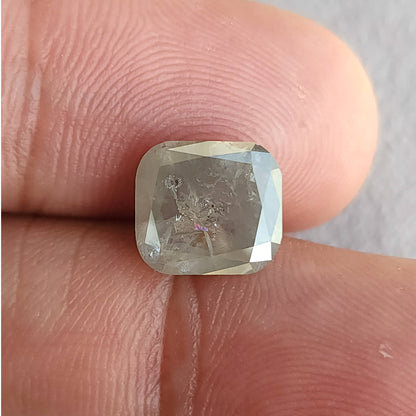 Front view of the cushion diamond on fingers, showing its rounded corners, internal marks and bright reflection along the right edge.