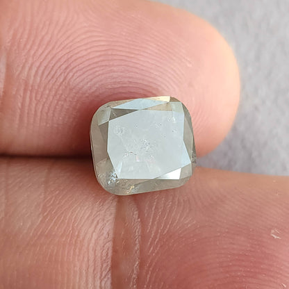 Alternate front angle of the cushion diamond on fingers, with a large bright table reflection and rounded square outline.
