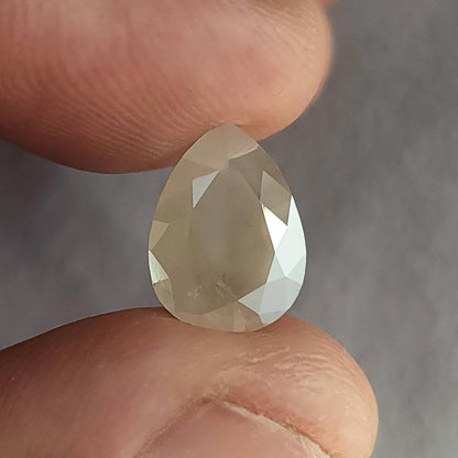 Table-side view of a pear-shaped ice gray diamond between fingers, with a muted central table and bright right border.
