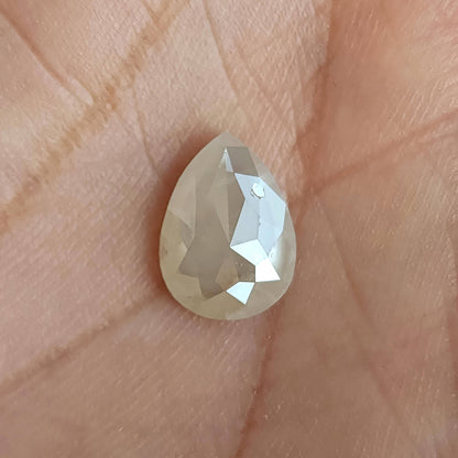 Rose-cut pavilion of a pear-shaped ice gray diamond resting upright on a hand, with a bright central facet.