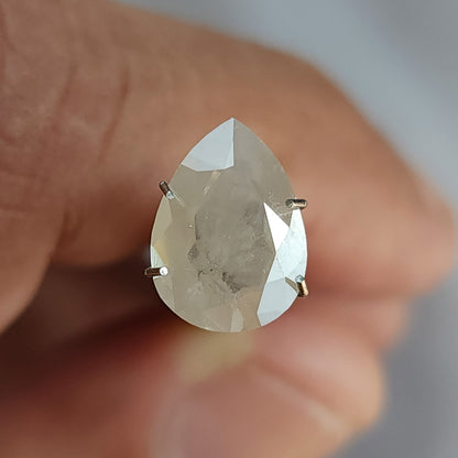 Table-side pear-shaped ice gray diamond supported by a temporary prong holder, with visible inclusions in the flat table.