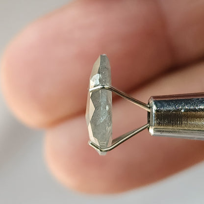 Thin side profile of the pear diamond in a temporary stone holder, showing its depth and the faceted surfaces on either side.