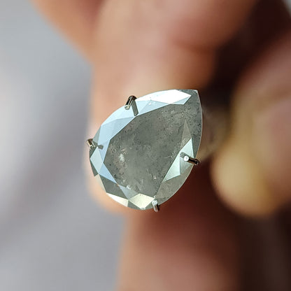 Front table-side view of the pear diamond in a temporary stone holder, with bright border facets and a gray included center.