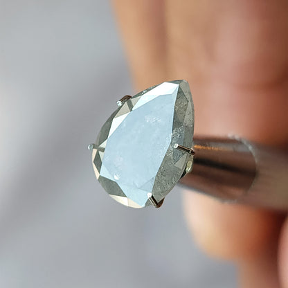 Pear diamond in a temporary holder with a broad pale reflection across the front table and darker border facets.