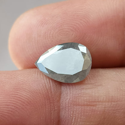 Pear diamond against fingertips with a bright reflection across the table side, showing its size and rounded-to-pointed outline.