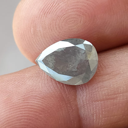 Alternate front view of the pear diamond on fingertips, showing its scale, gray center and pale reflections around the edges.