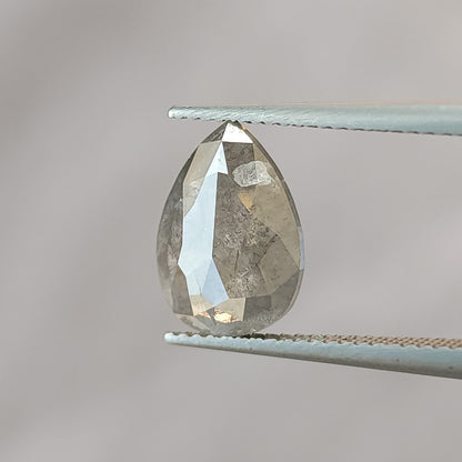 Rose-faceted pavilion side of the pear diamond in tweezers, showing large geometric reflections and visible inclusions.