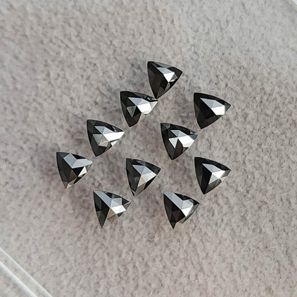 Black trillion diamonds on fabric with the converging triangular facets of their rose-cut pavilion sides visible.