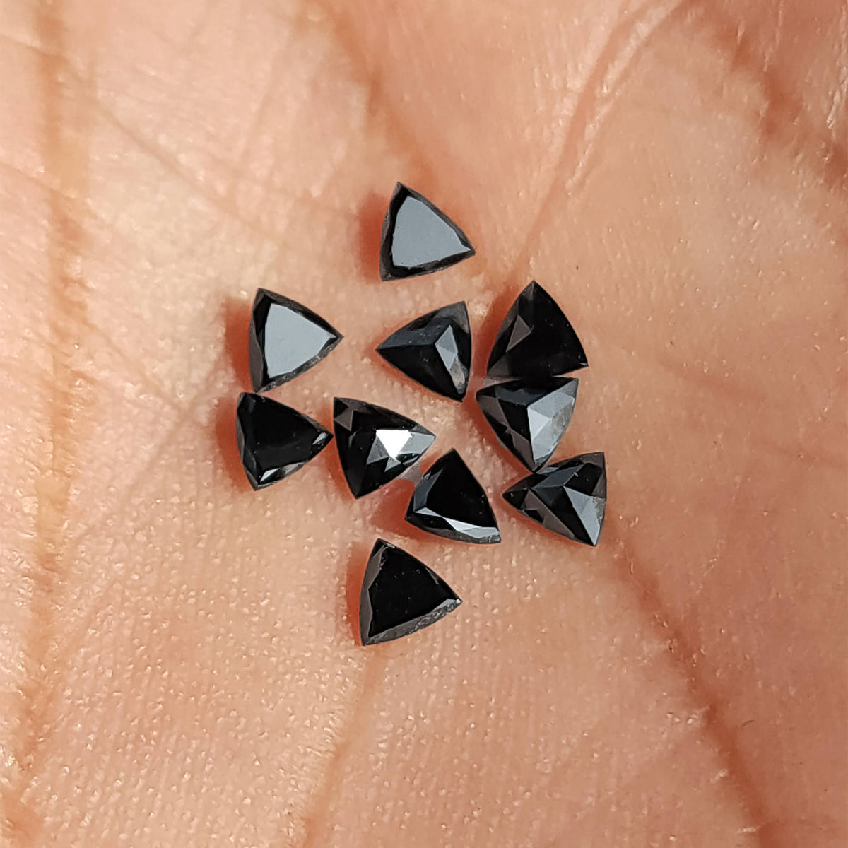 Close-up of black trillion diamonds on skin, with bright triangular reflections across several faces.