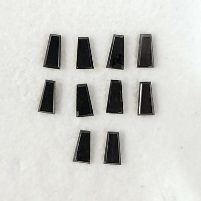 Flat reverse faces of black tapered diamonds arranged in rows on a pale surface.