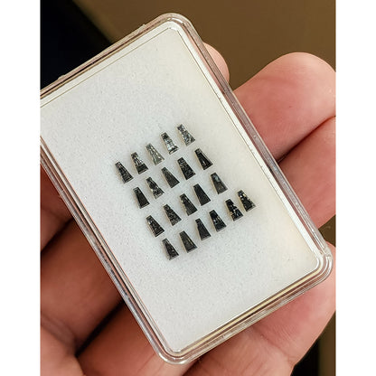 Display box of tapered baguette salt and pepper diamonds held on a hand for scale.