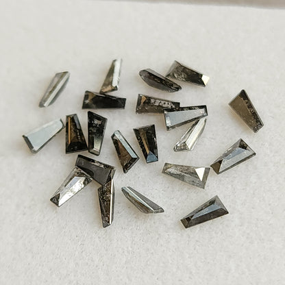 Small group of natural tapered baguette diamonds showing variation in smoky gray tone and salt and pepper inclusions.