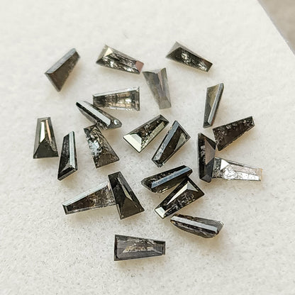 Loose arrangement of faceted tapered baguette diamonds with varied dark inclusion patterns.