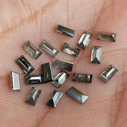 Alternate close view of diamond baguettes on a palm, showing varied gray inclusions and reflections.