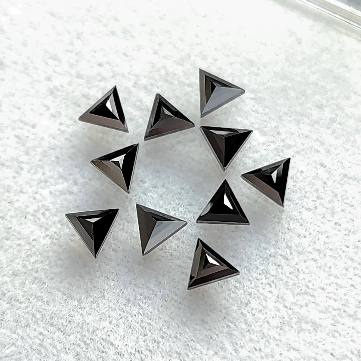 Black triangular diamonds on pale fabric with raised triangular facets converging toward their centers.