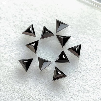 Black triangular diamonds on pale fabric with raised triangular facets converging toward their centers.