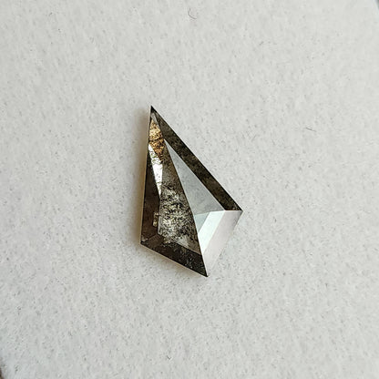Face-up view of a kite-shaped salt and pepper lab-grown diamond resting on a white textured background.