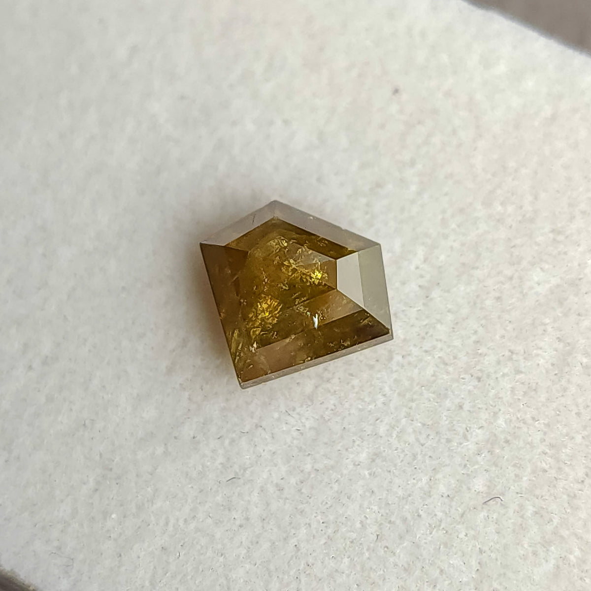 Oblique view of the warm yellow-brown shield diamond, showing its pointed lower edge and side profile.