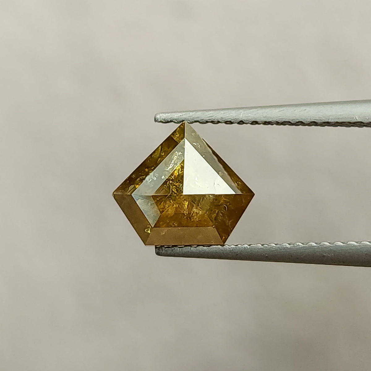 Face-up view of one usable side of the 2.08 ct shield-shaped natural diamond, showing its warm yellow-brown color and geometric facets.