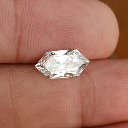 Elongated geometric hexagonal cut diamond held horizontally across fingers showing relative scale.