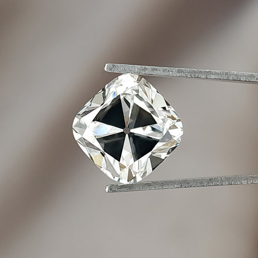 Face-up view of a colorless square cushion cut diamond held in metal tweezers against a neutral backdrop.