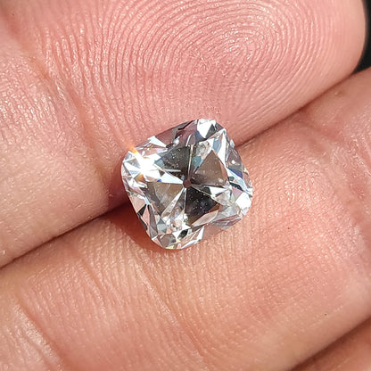 Tilted square cushion cut gem held in hand, showing surface brilliance and antique style faceting.