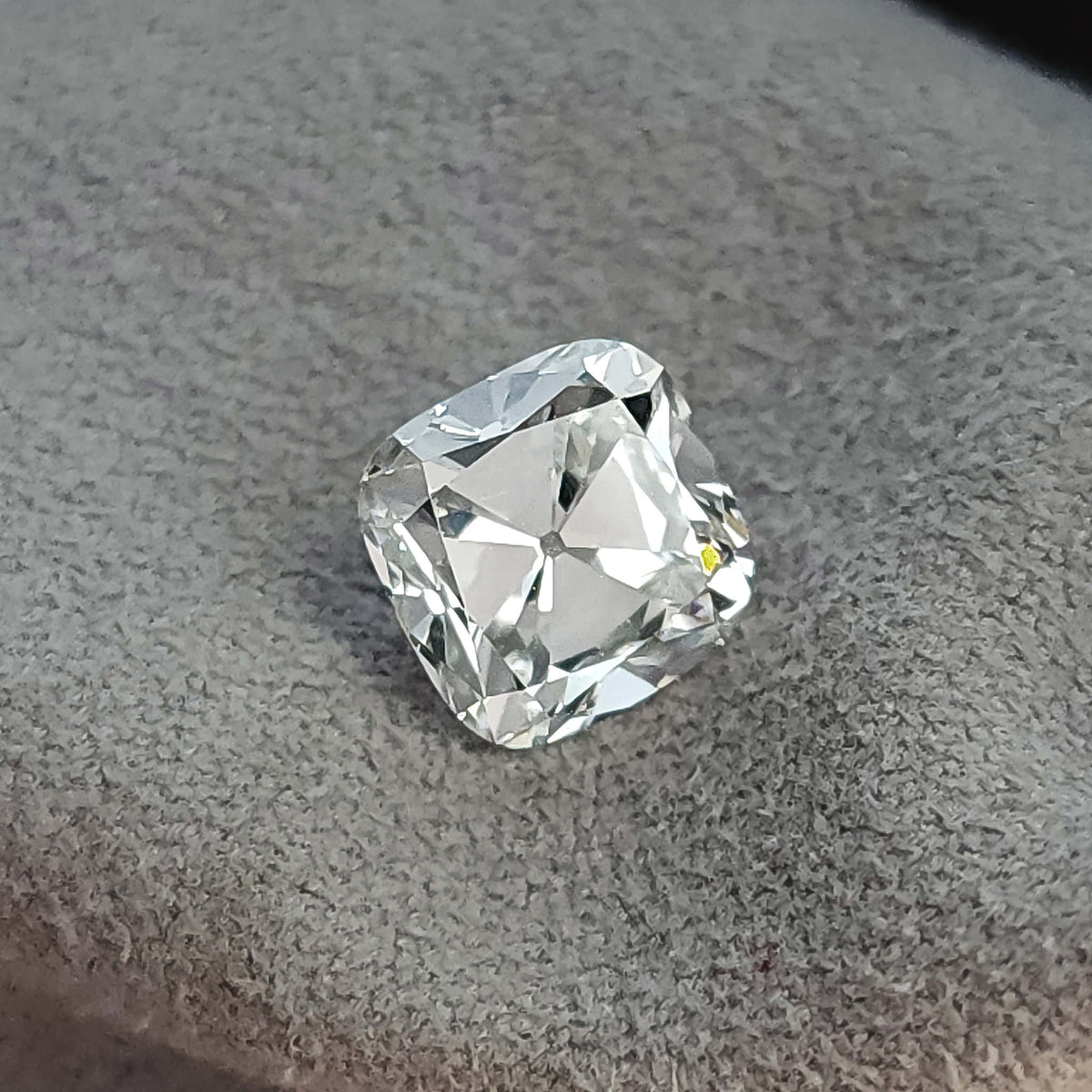 Loose square cushion cut stone displayed at an angle on a gray fabric background.