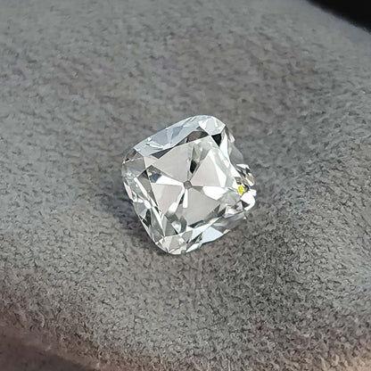 Loose square cushion cut stone displayed at an angle on a gray fabric background.